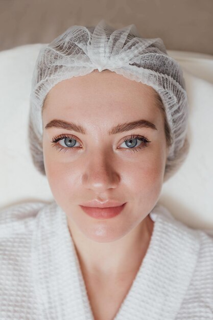 Portrait of young female in sterile hat in beauty clinic