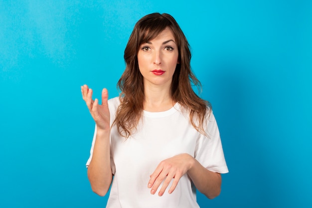 Portrait of a young friendly woman in casual t-shirt on blue. Emotional face