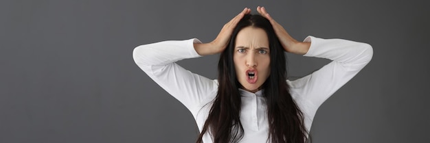 Portrait of young frowning displeased woman on gray background negative female emotions concept