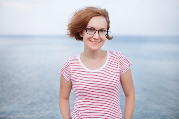 Portrait of a young girl on the background of the sea glasses and wind tousled hair smile and rest