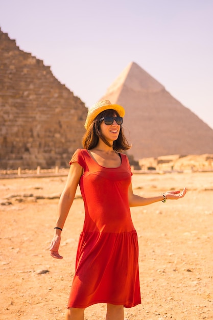 Portrait of a young girl in red dress at the pyramid of Cheops the largest pyramid