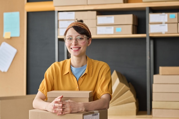 Portrait of young girl smiling at camera while working with parcels in storage room