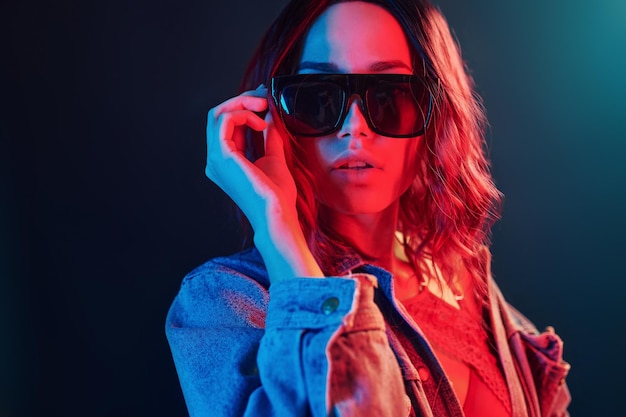 Portrait of young girl in sunglasses in red and blue neon in studio