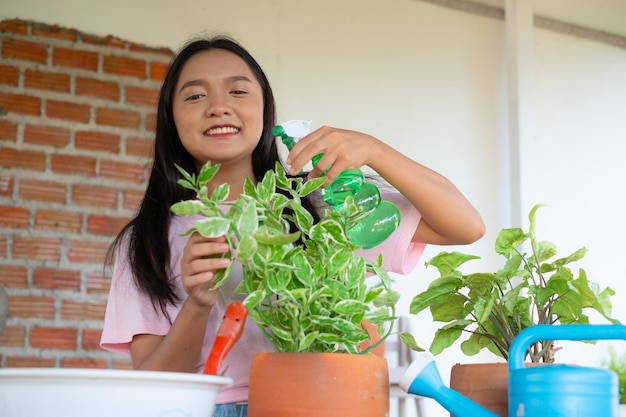 Portrait young girl watering green plants at home Asian girl