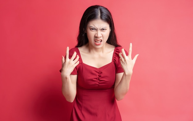 Portrait of young girl wearing red dress with expression on background