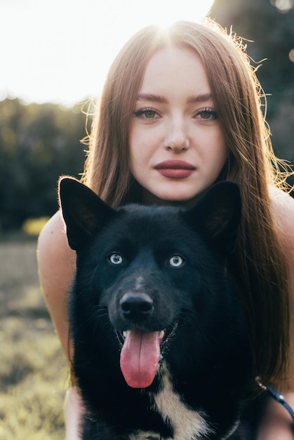 Portrait of a young girl with a European appearance in an embrace with a black dog Laika