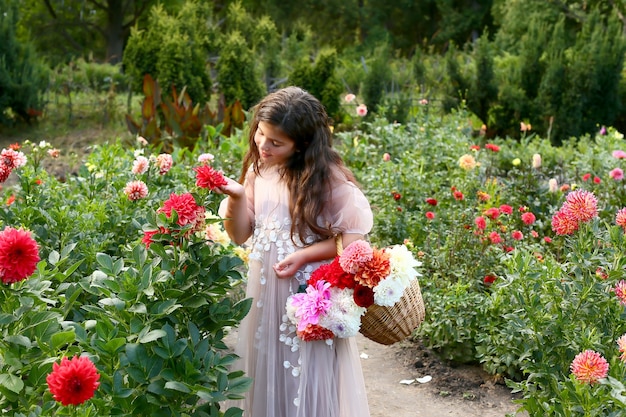 Portrait of young girl with flowers in the garden. beautiful girl among dahlia flowers