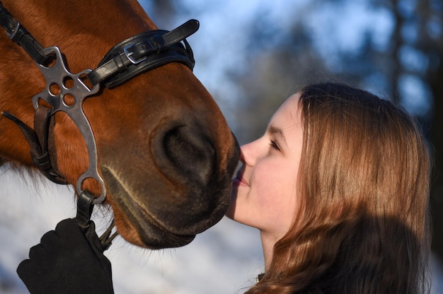 Portrait of a young girl with a horse in winter.