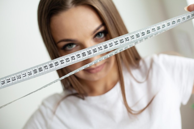 Portrait young girl with open mouth looking at a measuring tape