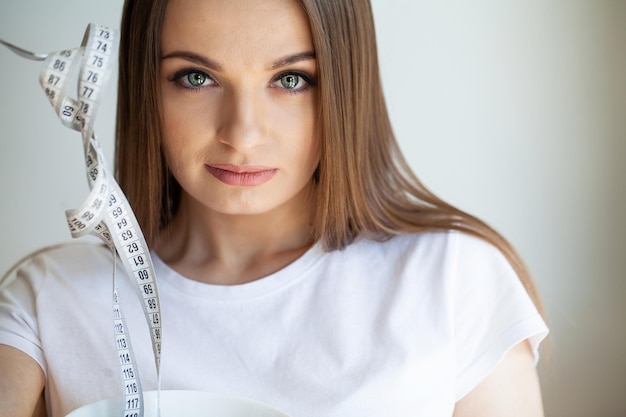 Portrait young girl with open mouth looking at a measuring tape