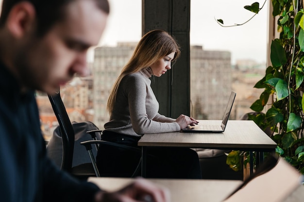 Portrait of a young girl working on a laptop sitting in a modern coworking space