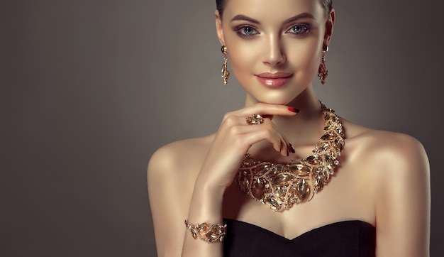 Portrait of young gorgeous woman dressed in a jewelry set of necklace, ring, bracelet and earrings. Pretty blue eyed model is demonstrating an attractive makeup and manicure.