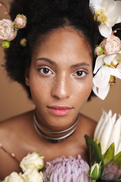 Portrait of young half-naked freckled african american woman posing with flowers 