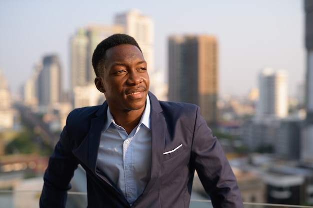 Portrait of young handsome African businessman against view of the city