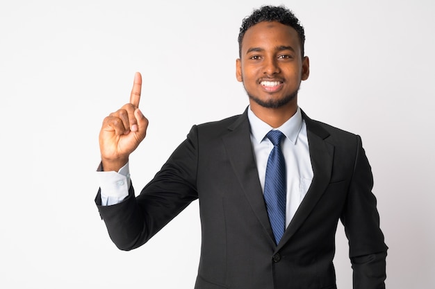 Portrait of young handsome African businessman in suit against white wall