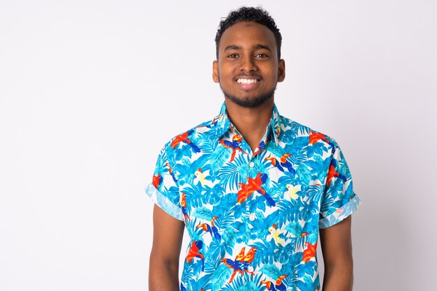 Portrait of young handsome African tourist man against white wall