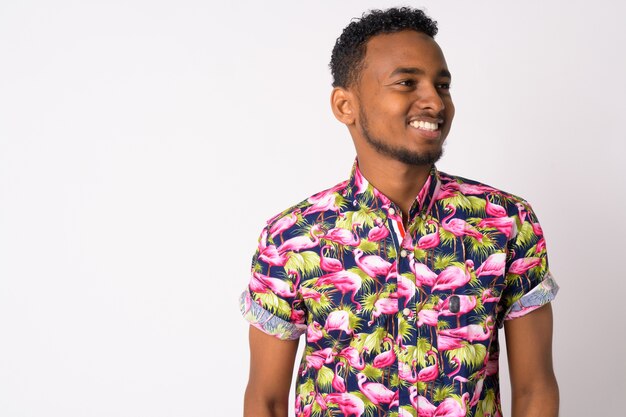 Portrait of young handsome African tourist man against white wall