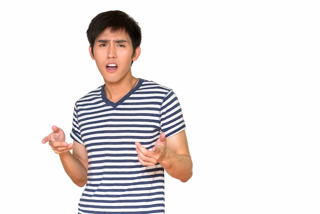 Portrait of young handsome Asian man isolated against white wall