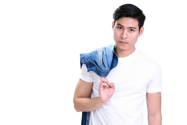 Portrait of young handsome Asian man in white t-shirt holding jean shirt