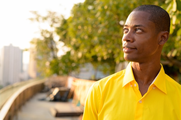 Portrait of young handsome bald African businessman at the terrace rooftop