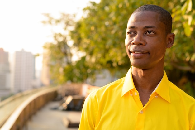 Portrait of young handsome bald African businessman at the terrace rooftop