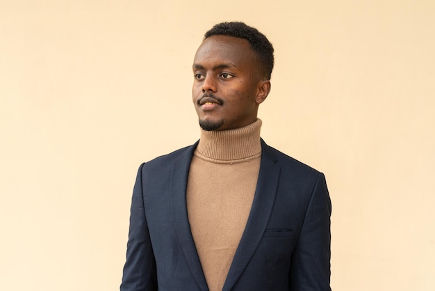 Portrait of young handsome black businessman thinking