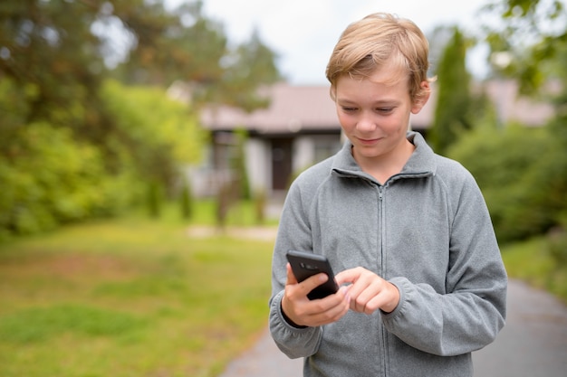 Portrait of young handsome boy with blond hair at home outdoors