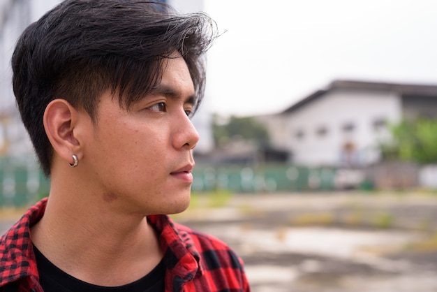 Portrait of young handsome Filipino hipster man in the city streets outdoors