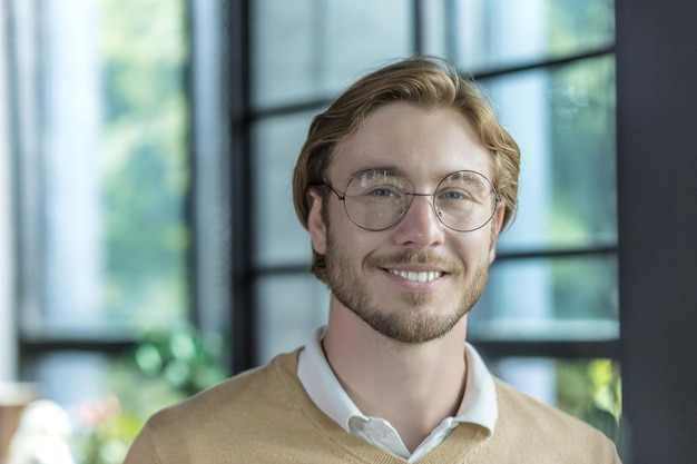 Portrait of a young handsome freelancer man a blond businessman looking at the camera and smiling a