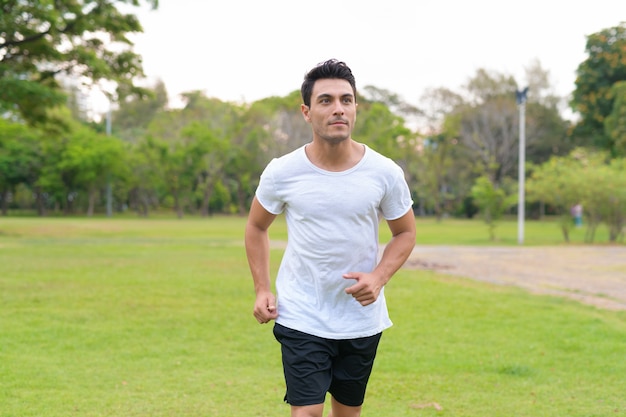 Portrait of young handsome Hispanic man in the park outdoors