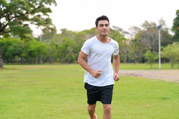 Portrait of young handsome Hispanic man in the park outdoors