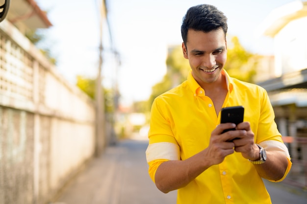 Portrait of young handsome Indian man in the streets outdoors