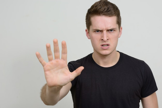 Portrait of young handsome man against white wall