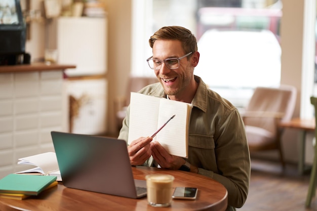 Portrait of young handsome man in glasses private tutor teaching student online pointing at his