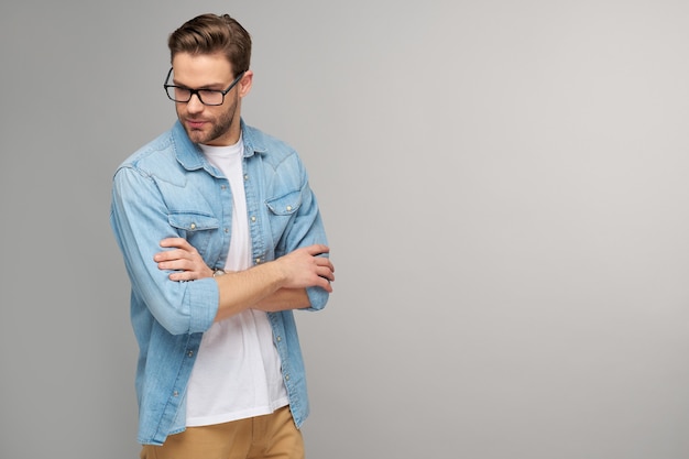 Portrait of young handsome man in jeans shirt over light wall