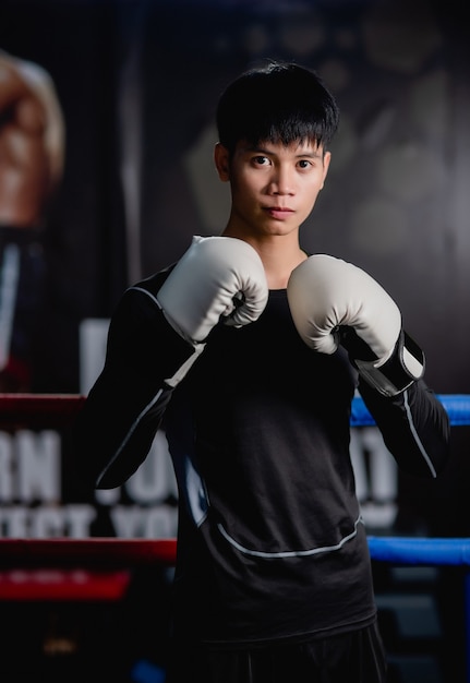 Portrait young handsome man in sportswear and white boxing gloves standing pose on canvas in fitness gym, Healthy man workout boxing class,, 