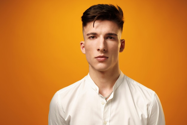 Portrait of a young handsome man teenager against yellow background