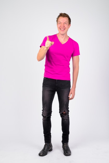 Portrait of young handsome man wearing purple shirt against white wall