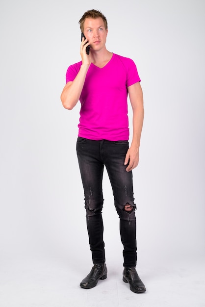 Portrait of young handsome man wearing purple shirt against white wall