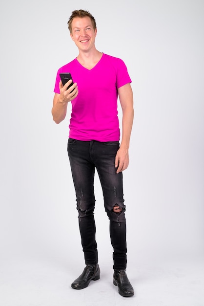 Portrait of young handsome man wearing purple shirt against white wall