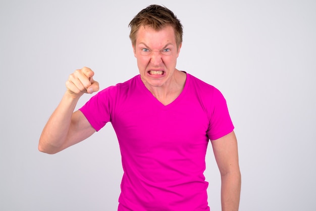 Portrait of young handsome man wearing purple shirt against white wall