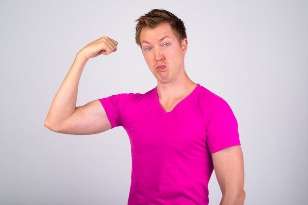 Portrait of young handsome man wearing purple shirt against white wall