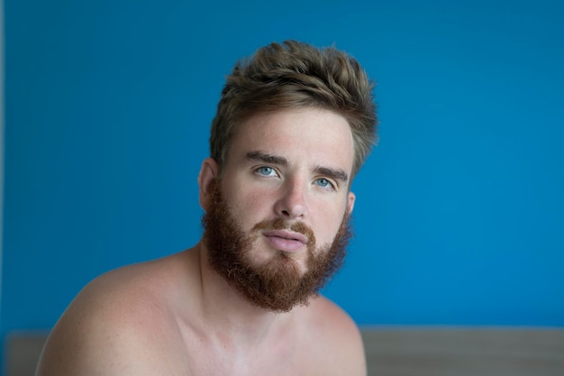 Portrait of a young handsome man without clothes on a blue background