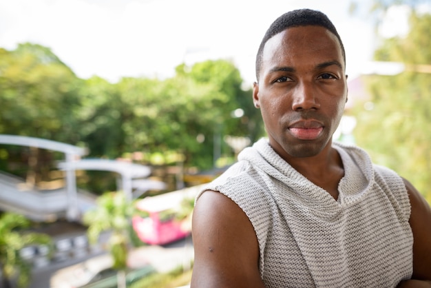 Portrait of young handsome muscular African man ready for gym against view of the city streets