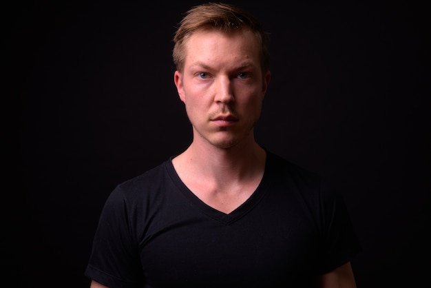 portrait of young handsome Scandinavian man on black