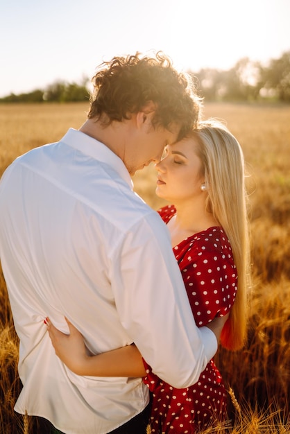 Portrait of young happy couple hugging on the field on the sunset Enjoying time together