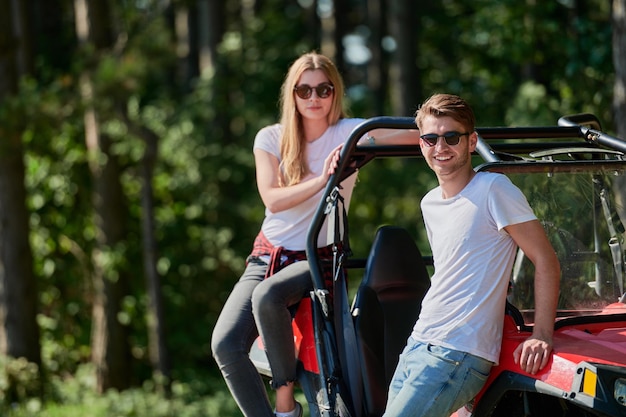 portrait of young happy excited couple enjoying beautiful sunny day while driving a off road buggy car on mountain nature