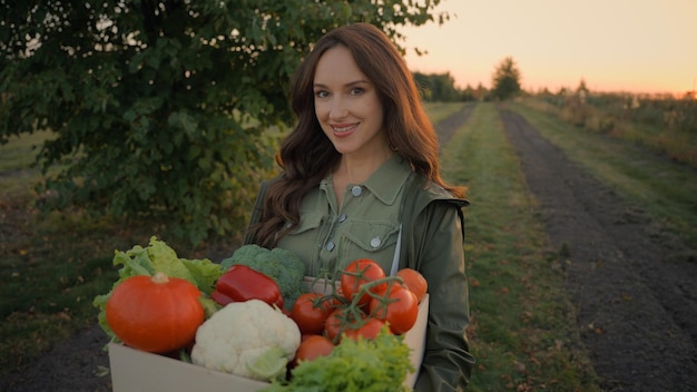 Photo portrait young happy joyful caucasian girl lady woman female farmer carry box freshly picked