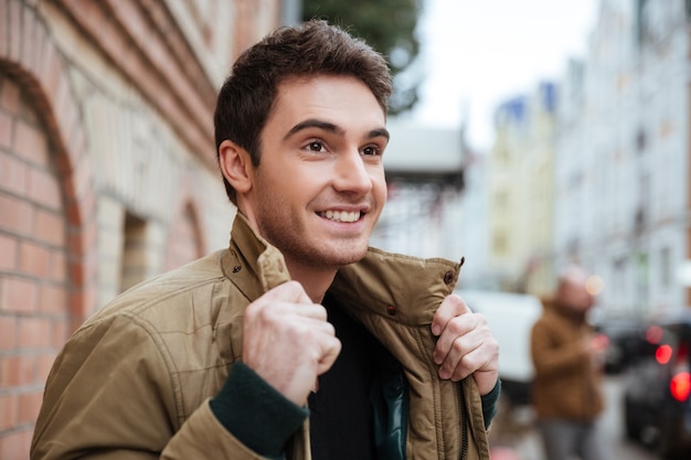 Portrait of young happy man walking on the street and looking aside.