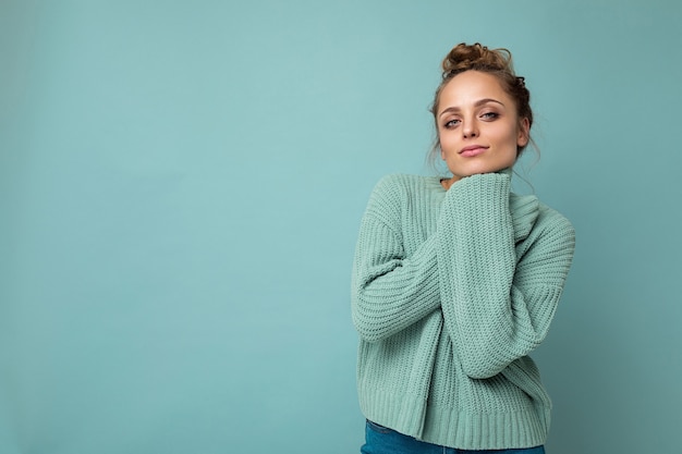 Portrait of young happy positive satisfied cute cozy attractive beautiful blonde woman with sincere emotions wearing casual blue pullover